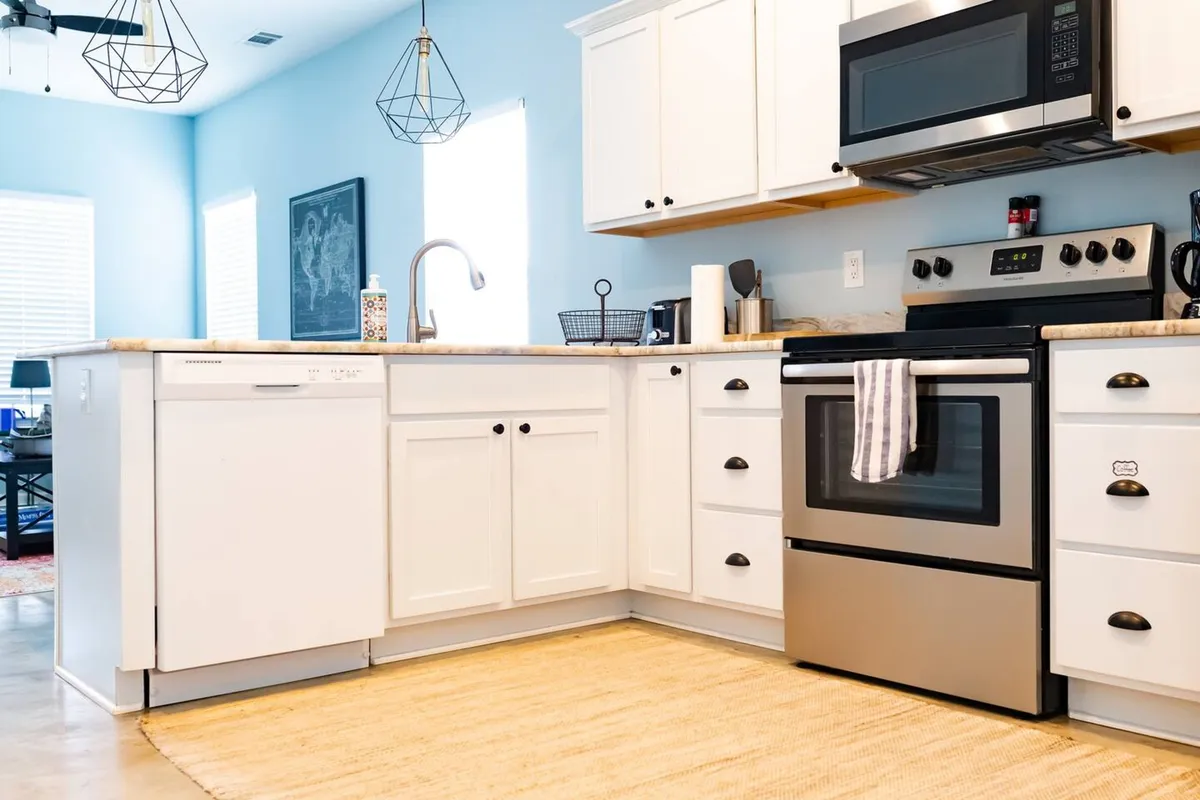 The hero image showcases a bright, modern kitchen with gleaming white cabinetry, stainless steel appliances, and a spacious island countertop, creating an inviting space for cooking and gathering. The cheerful atmosphere is perfect for preparing family breakfasts, holiday feasts, or sharing laughter over intimate dinners.