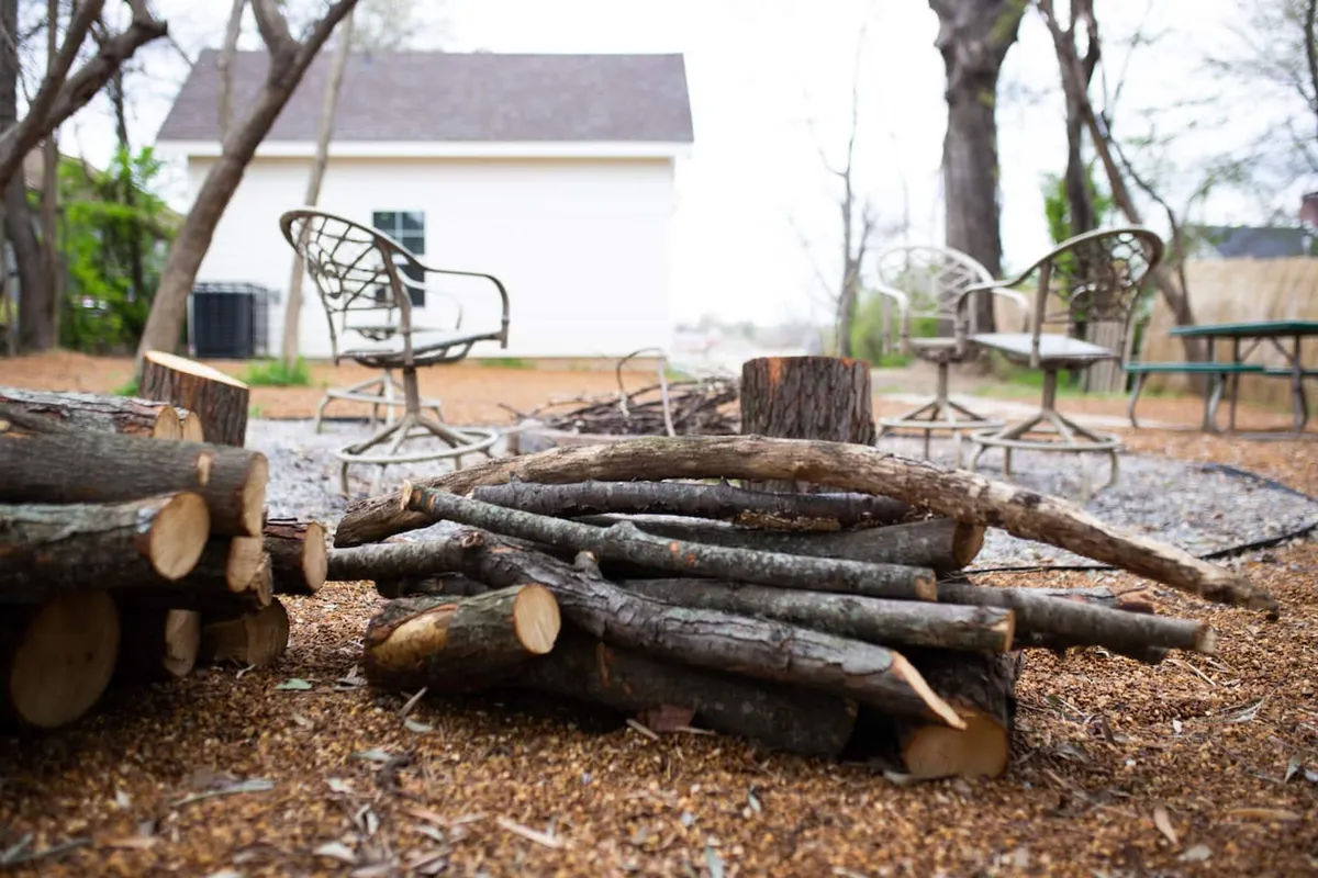 A close-up of a seating arrangement encircling a fire pit with a neatly stacked supply of firewood in the background. The mood is intimate and relaxed, evoking the experience of gathering with friends or family to share stories or roast marshmallows.