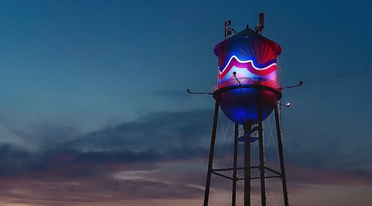 This atmospheric exterior shot captures the neighborhood’s water tower at sunset, bathed in colorful lighting. The scene suggests opportunities for evening strolls, photography, and gathering with friends in a dynamic local setting.